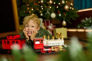 Kid With Model Train by Christmas Tree